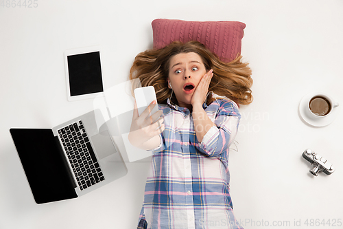 Image of Emotional caucasian woman using gadgets isolated on white studio background, technologies connecting people. Crazy shocked