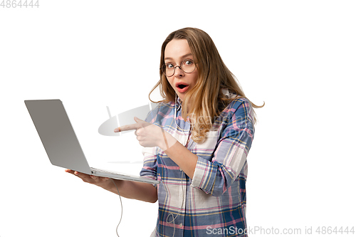 Image of Emotional caucasian woman using laptop on white studio background, technologies. Shocked pointing