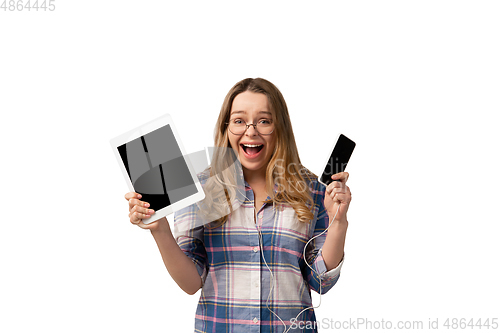 Image of Emotional caucasian woman using gadgets on white studio background, technologies. Crazy happy shows tablet and smartphone