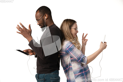 Image of Emotional man and woman using gadgets on white studio background, technologies connecting people. Gaming, shopping, online meeting