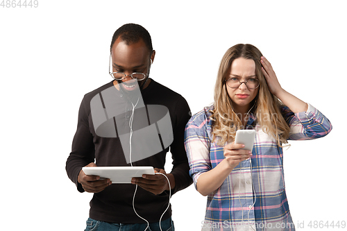 Image of Emotional man and woman using gadgets on white studio background, technologies connecting people. Gaming, shopping, online meeting