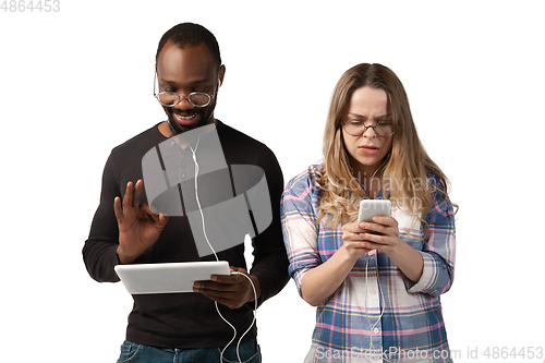 Image of Emotional man and woman using gadgets on white studio background, technologies connecting people. Gaming, shopping, online meeting