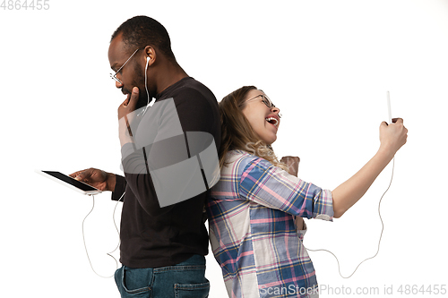 Image of Emotional man and woman using gadgets on white studio background, technologies connecting people. Gaming, shopping, online meeting