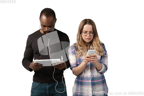 Image of Emotional man and woman using gadgets on white studio background, technologies connecting people. Gaming, shopping, online meeting