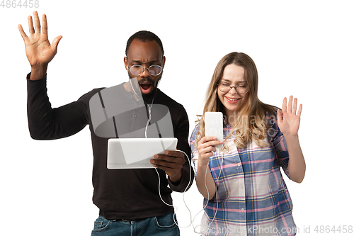 Image of Emotional man and woman using gadgets on white studio background, technologies connecting people. Gaming, shopping, online meeting