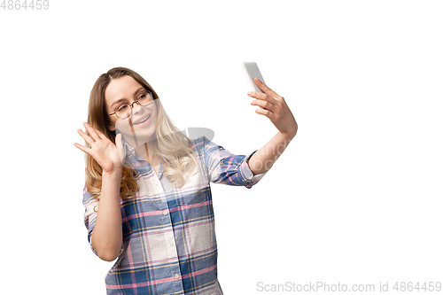 Image of Emotional caucasian woman using smartphone isolated on white studio background, technologies. Taking selfie