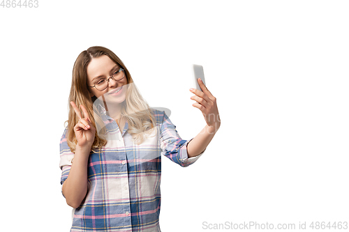 Image of Emotional caucasian woman using smartphone isolated on white studio background, technologies. Taking selfie