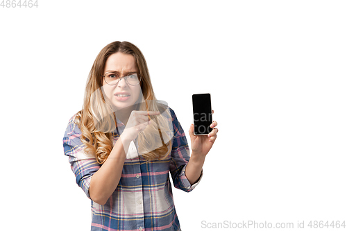 Image of Emotional caucasian woman using smartphone isolated on white studio background, technologies. Disguasted, pointing