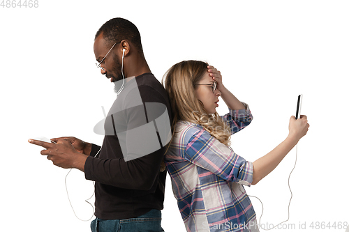 Image of Emotional man and woman using gadgets on white studio background, technologies connecting people. Gaming, shopping, online meeting