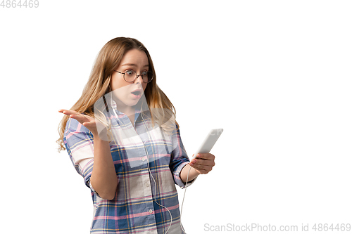 Image of Emotional caucasian woman using smartphone isolated on white studio background, technologies. Listen to music, shocked