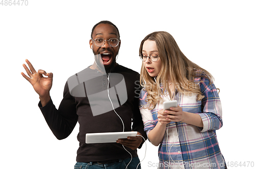 Image of Emotional man and woman using gadgets on white studio background, technologies connecting people. Gaming, shopping, online meeting