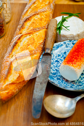 Image of French cheese and fresh  baguette on a wood cutter