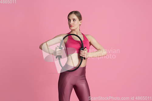 Image of Beautiful young female athlete practicing on pink studio background, monochrome portrait