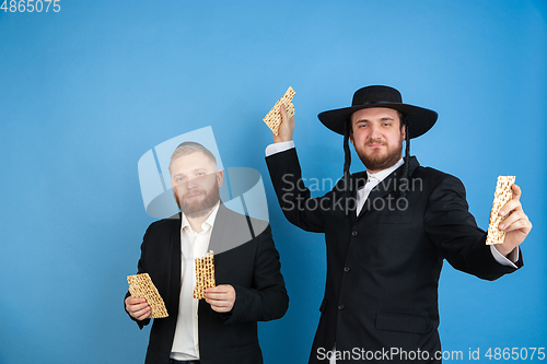 Image of Portrait of a young orthodox jewish men isolated on blue studio background, meeting the Passover