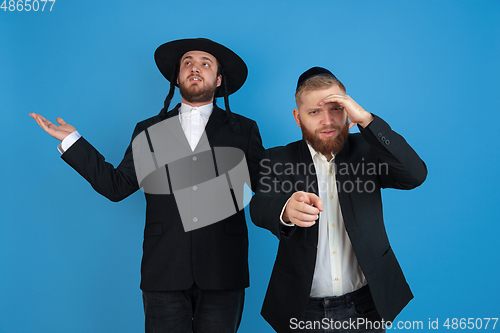 Image of Portrait of a young orthodox jewish men isolated on blue studio background, meeting the Passover, astonished