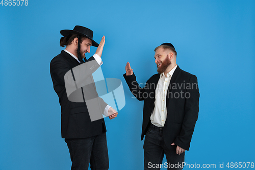 Image of Portrait of a young orthodox jewish men isolated on blue studio background, meeting the Passover