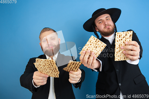 Image of Portrait of a young orthodox jewish men isolated on blue studio background, meeting the Passover