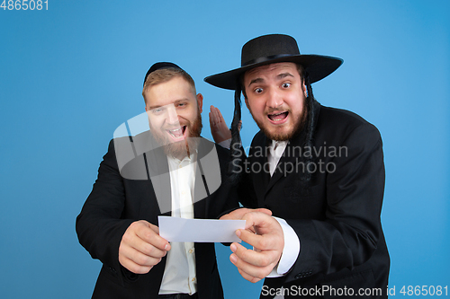 Image of Portrait of a young orthodox jewish men isolated on blue studio background, meeting the Passover, winners