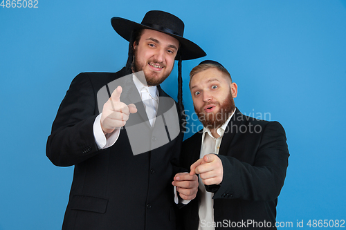 Image of Portrait of a young orthodox jewish men isolated on blue studio background, meeting the Passover