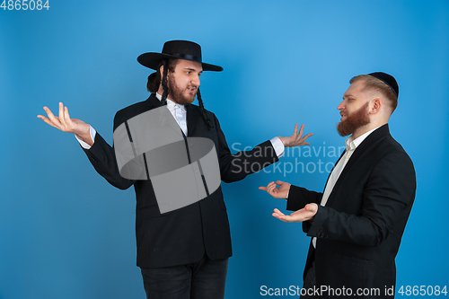 Image of Portrait of a young orthodox jewish men isolated on blue studio background, meeting the Passover