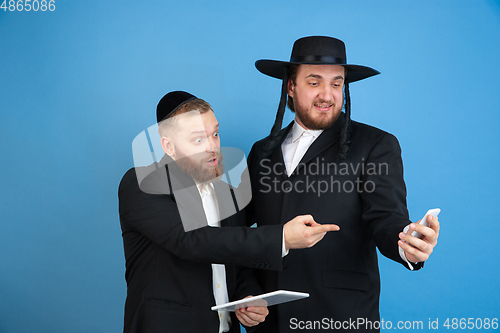 Image of Portrait of a young orthodox jewish men isolated on blue studio background, meeting the Passover, astonished