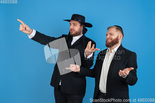 Image of Portrait of a young orthodox jewish men isolated on blue studio background, meeting the Passover