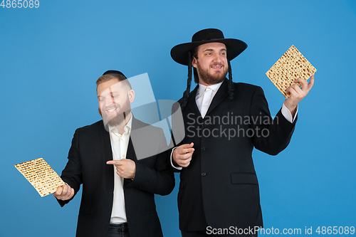 Image of Portrait of a young orthodox jewish men isolated on blue studio background, meeting the Passover