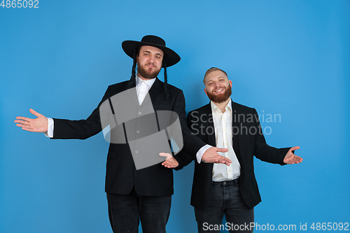 Image of Portrait of a young orthodox jewish men isolated on blue studio background, meeting the Passover