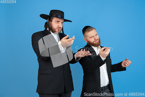 Image of Portrait of a young orthodox jewish men isolated on blue studio background, meeting the Passover