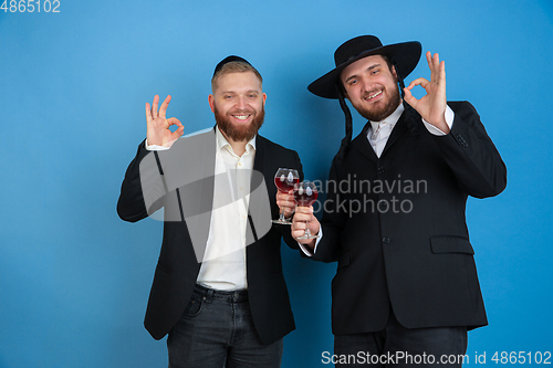 Image of Portrait of a young orthodox jewish men isolated on blue studio background, meeting the Passover