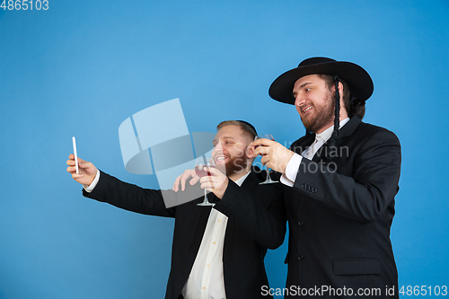 Image of Portrait of a young orthodox jewish men isolated on blue studio background, meeting the Passover