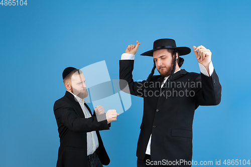 Image of Portrait of a young orthodox jewish men isolated on blue studio background, meeting the Passover