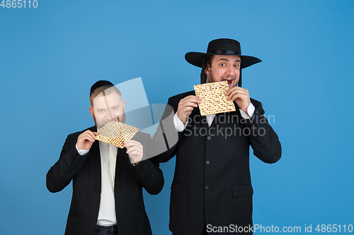 Image of Portrait of a young orthodox jewish men isolated on blue studio background, meeting the Passover