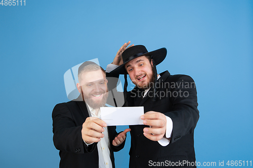 Image of Portrait of a young orthodox jewish men isolated on blue studio background, meeting the Passover, winners