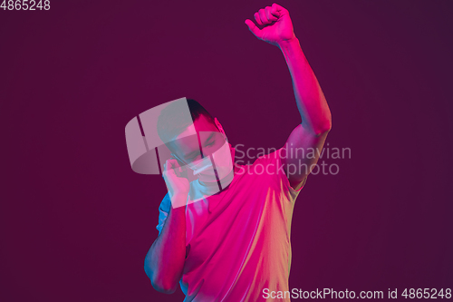 Image of Caucasian man\'s portrait isolated on pink-purple studio background in neon light, wearing face mask
