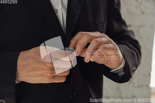 Image of Close up of caucasian male hands, wearing classic black jacket