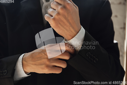Image of Close up of caucasian male hands, wearing classic black jacket