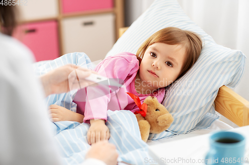 Image of doctor measuring sick girl's temperature at home