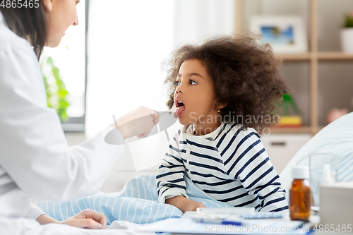 Image of doctor checking sick girl's throat at home