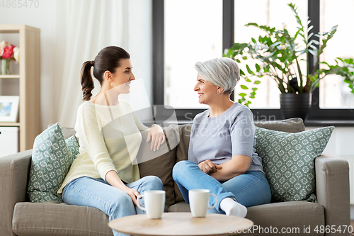 Image of senior mother with adult daughter talking at home