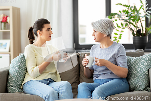 Image of senior mother and adult daughter drinking coffee