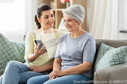 Image of daughter and senior mother with smartphone at home