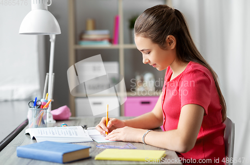 Image of student girl with ruler drawing line in notebook