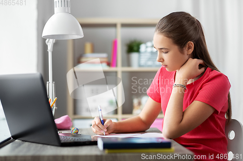 Image of teenage student girl writing to notebook at home