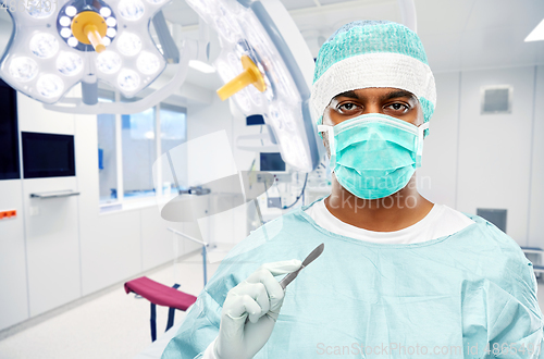 Image of indian surgeon with scalpel over operating room