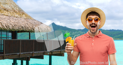 Image of happy man in straw hat with juice on beach