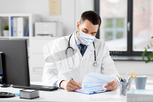 Image of smiling male doctor with clipboard at hospital