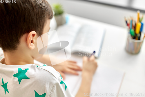 Image of close up of boy writing to notebook at home