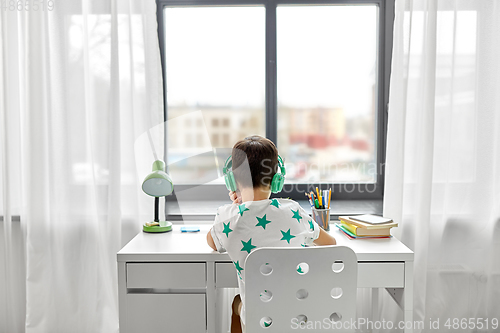 Image of boy in headphones with textbook learning at home