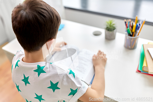 Image of boy with earphones and textbook learning at home